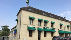 Un edificio con un letrero que dice "HOTEL de la Mare" y un área de estacionamiento con un letrero que indica "ENTREE PARKING (passer devant le badge avant)".