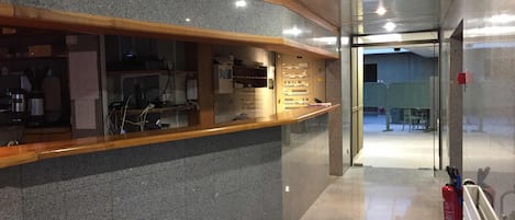 Zona de recepción con mostrador de granito, paneles de madera y un extintor.