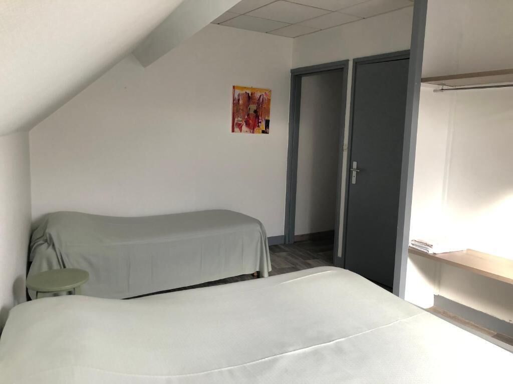 Et værelse med en seng, et lille bord, et garderobeskab og et billede på væggen.