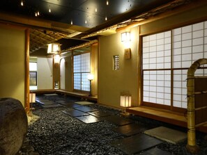 Un interior japonés tradicional con suelo de tatami, puertas correderas e iluminación tenue.