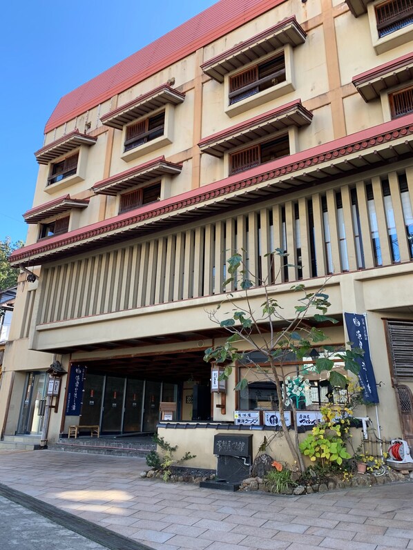 A multi-story building with a red roof, large windows, and a traditional facade.