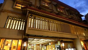 A traditional Japanese building with a covered entrance, wooden lattice windows, and a tiled floor. - TOKIWAYA Ryokan (Nozawaonsen)
