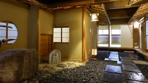 A traditional Japanese interior with tatami flooring, a stone lantern, and sliding doors. - TOKIWAYA Ryokan (Nozawaonsen)