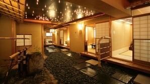 A traditional Japanese interior with tatami flooring, sliding doors, and a stone pathway. - TOKIWAYA Ryokan (Nozawaonsen)