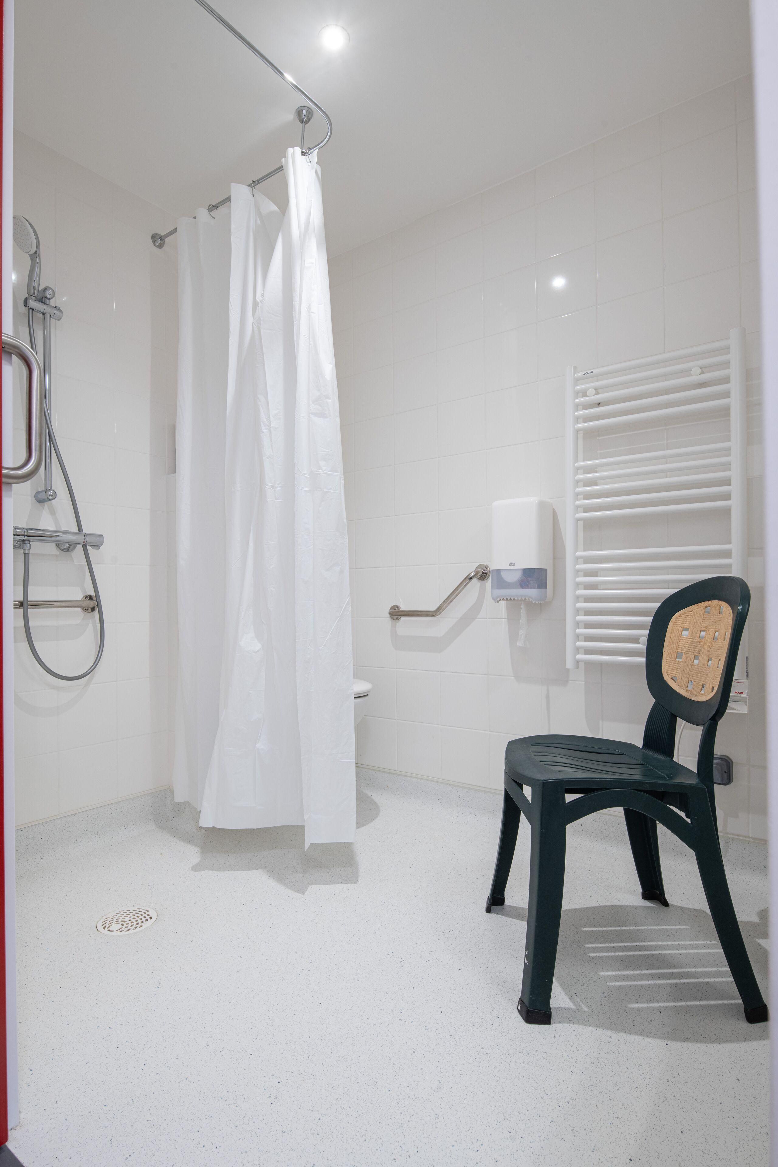 Un baño con ducha, inodoro y una silla.