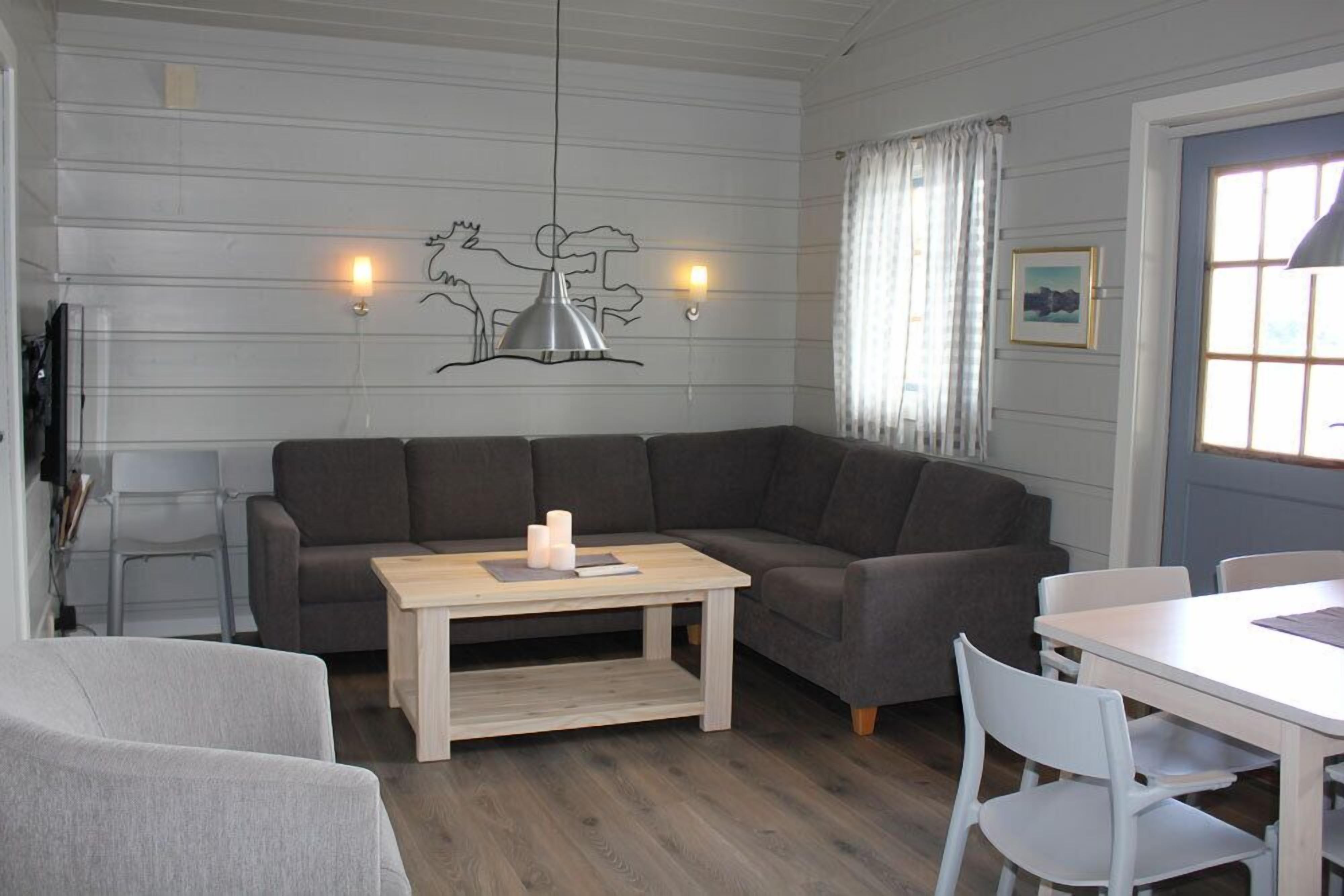 A modern living room with a sectional sofa, a wooden coffee table, and a dining area with white chairs.