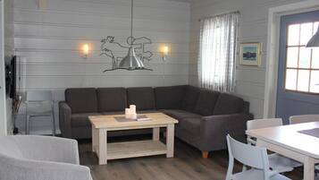 A modern living room with a sectional sofa, a wooden coffee table, and a dining area with white chairs.