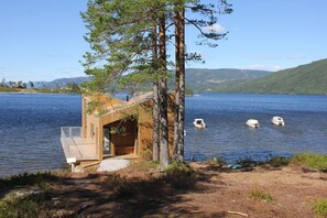 A wooden cabin by a lake with boats in the water. - Nisser Hyttegrend Og Camping (Nissedal)