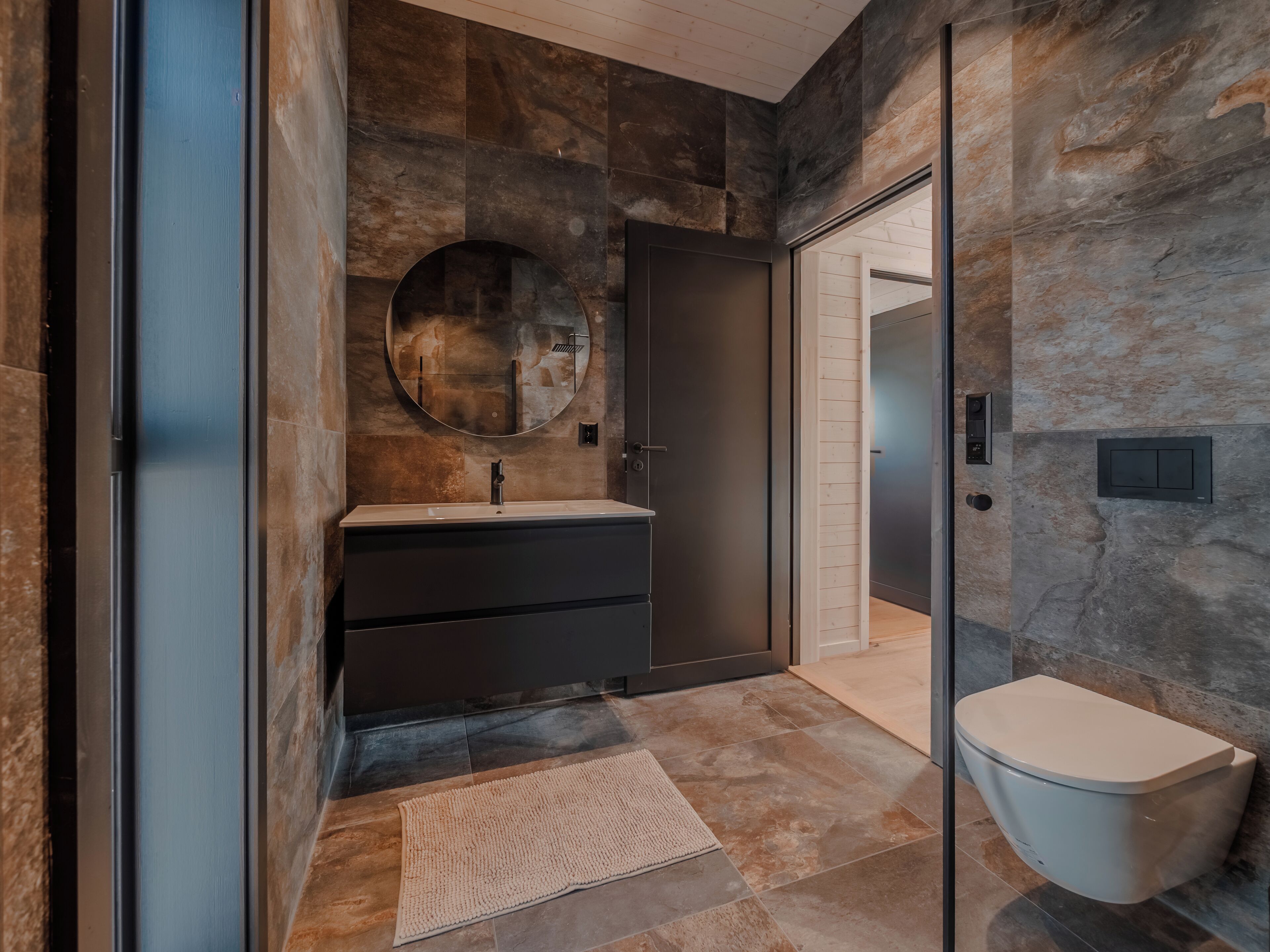 Ein modernes Badezimmer mit großem Spiegel, Waschbecken und Toilette.