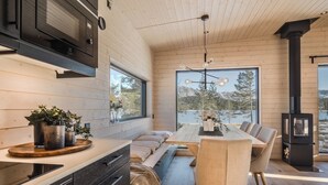 A modern kitchen with wooden cabinetry, a built-in stove, and a dining area with a large table and chairs.