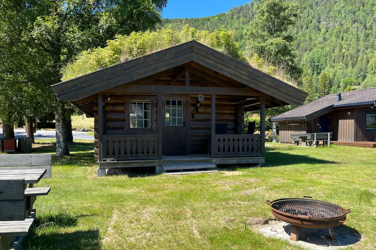 A rustic cabin with a porch, a fire pit, and a picnic table.