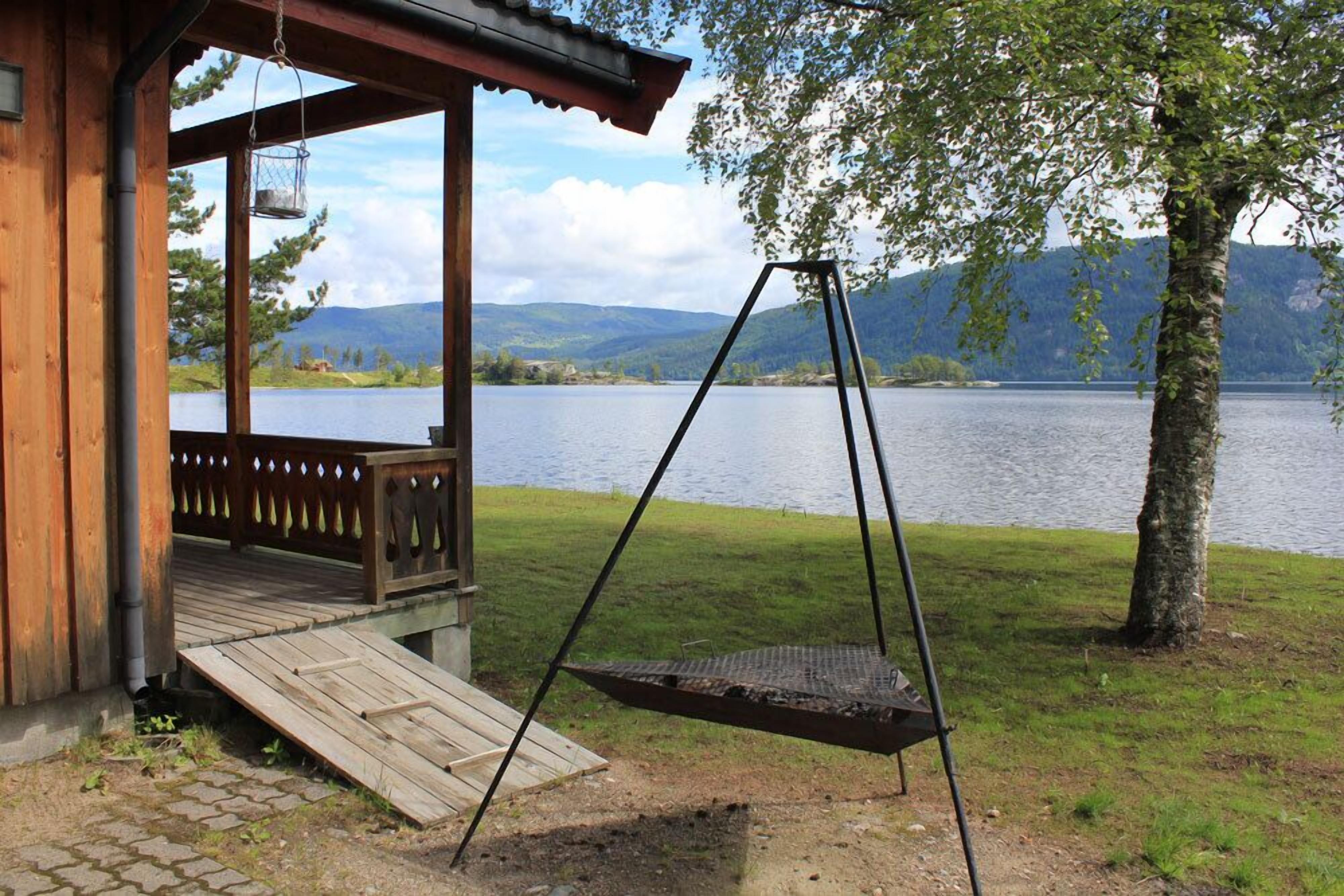A wooden cabin with a porch overlooking a lake and mountains.