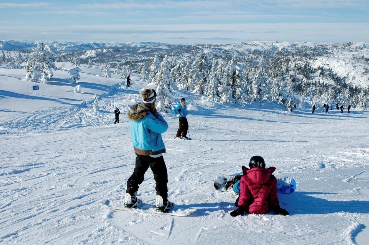 A snowy ski slope with skiers and snowboarders.