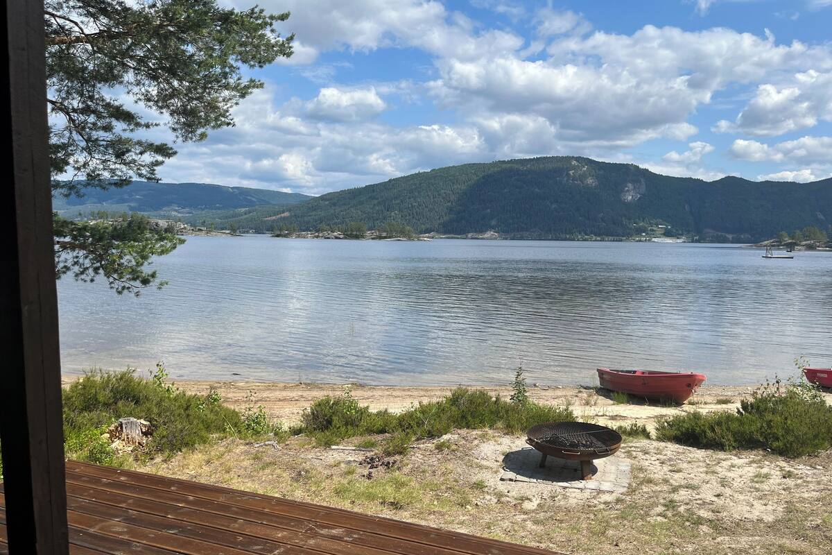 A lakeside view with boats, a grill, and a wooden deck.