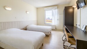 Habitación de hotel con dos camas, un escritorio, un televisor y un ventanal con cortinas.