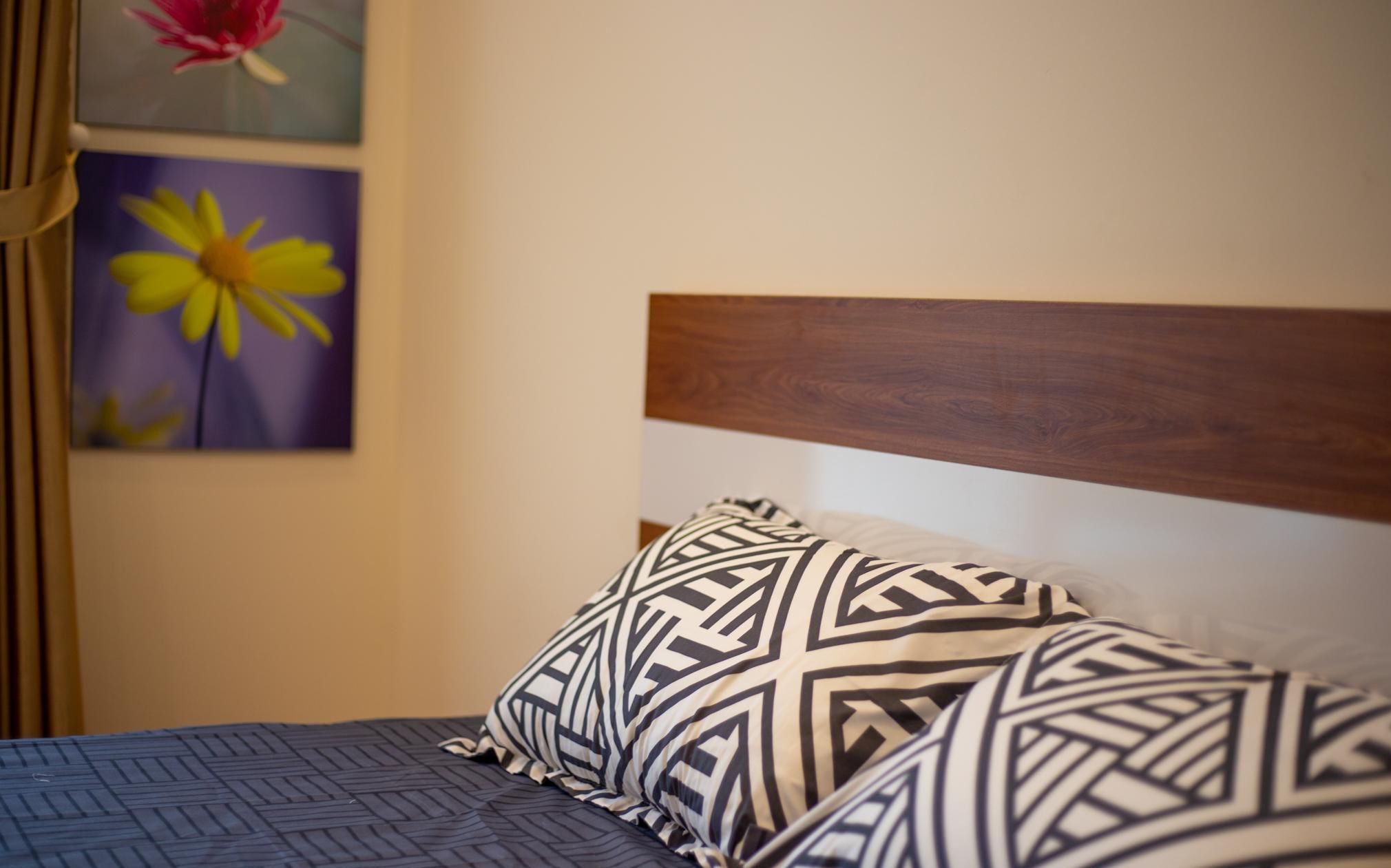 Ein Bett mit einem geometrisch gemusterten Kissen und einer dunkelblauen, strukturierten Bettdecke.