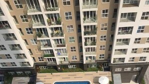 En pool på taket, omgiven av solstolar och parasoller, med höga bostadshus i bakgrunden.