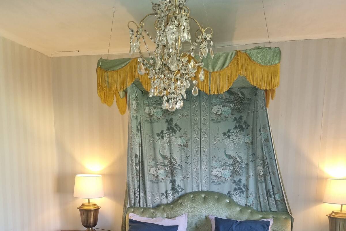 A bed with a green canopy and two bedside lamps.