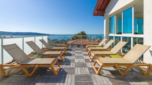 Eine Terrasse mit Liegestühlen, die auf einen schönen Meerblick ausgerichtet ist.