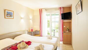 Habitación de hotel con dos camas, televisor, escritorio y ventana con cortinas.