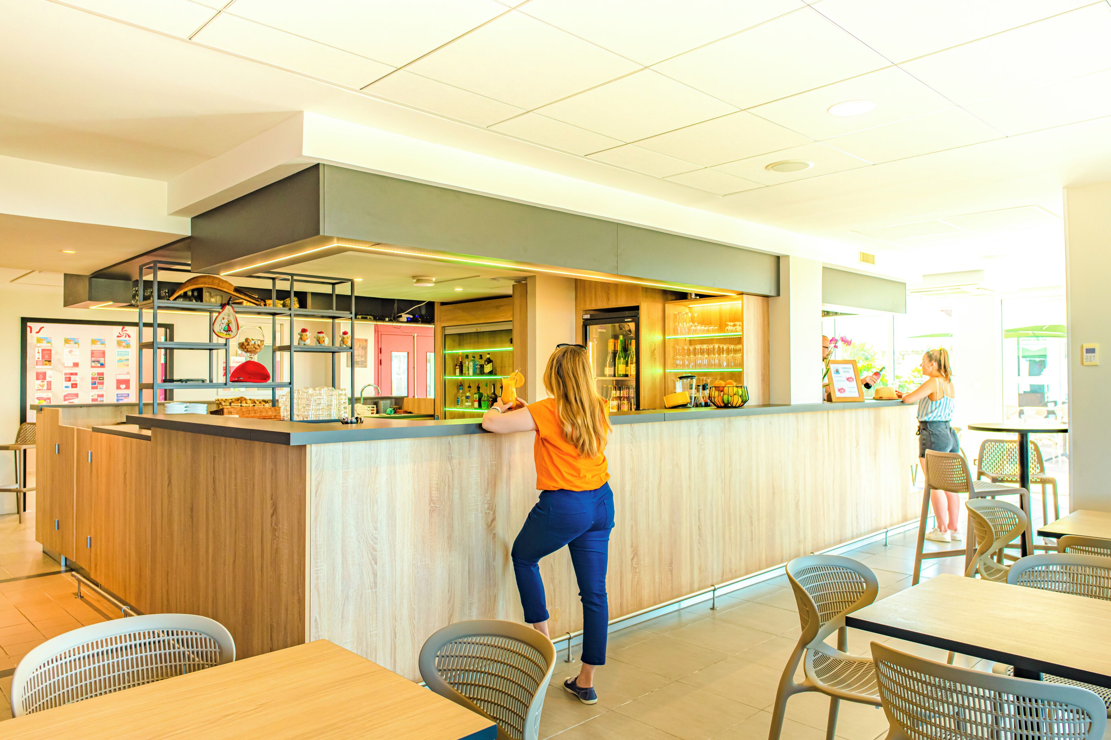 L'intérieur d'un café moderne, avec un comptoir en bois, un espace salon et des panneaux d'affichage où figure le menu.