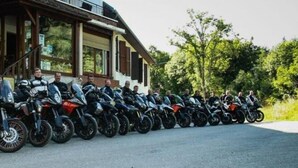 Une rangée de motos est garée devant un bâtiment doté d’une grande fenêtre et d’une façade en briques.