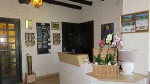 Un espace d’accueil avec un comptoir de réception en bois, un panier en osier, une lampe blanche et une carte encadrée accrochée au mur.