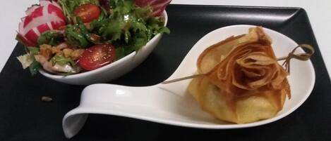 A white plate with a salad and a pastry on a black tray.