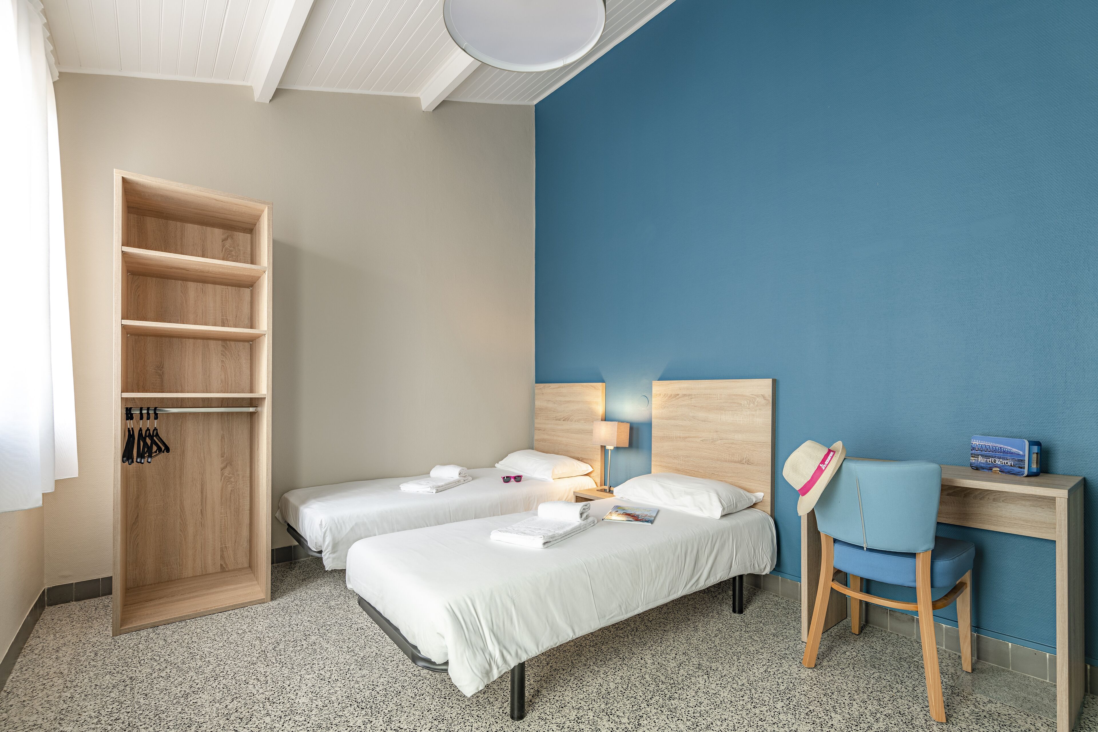 Une chambre d’hôtel avec deux lits, une armoire, un bureau et une chaise.