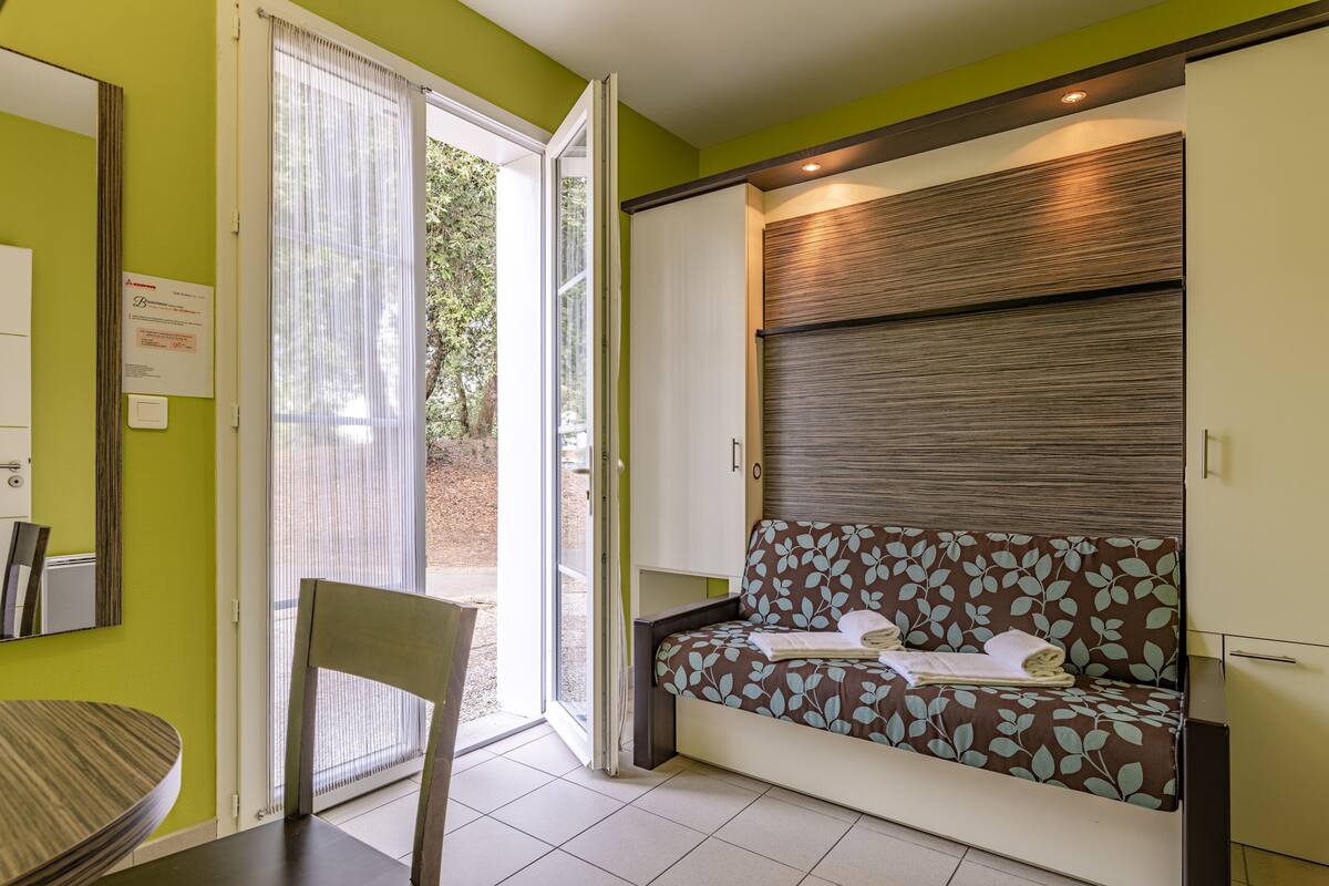 Une pièce comprenant un canapé, un fauteuil, une table et une porte coulissante donnant sur un espace extérieur.