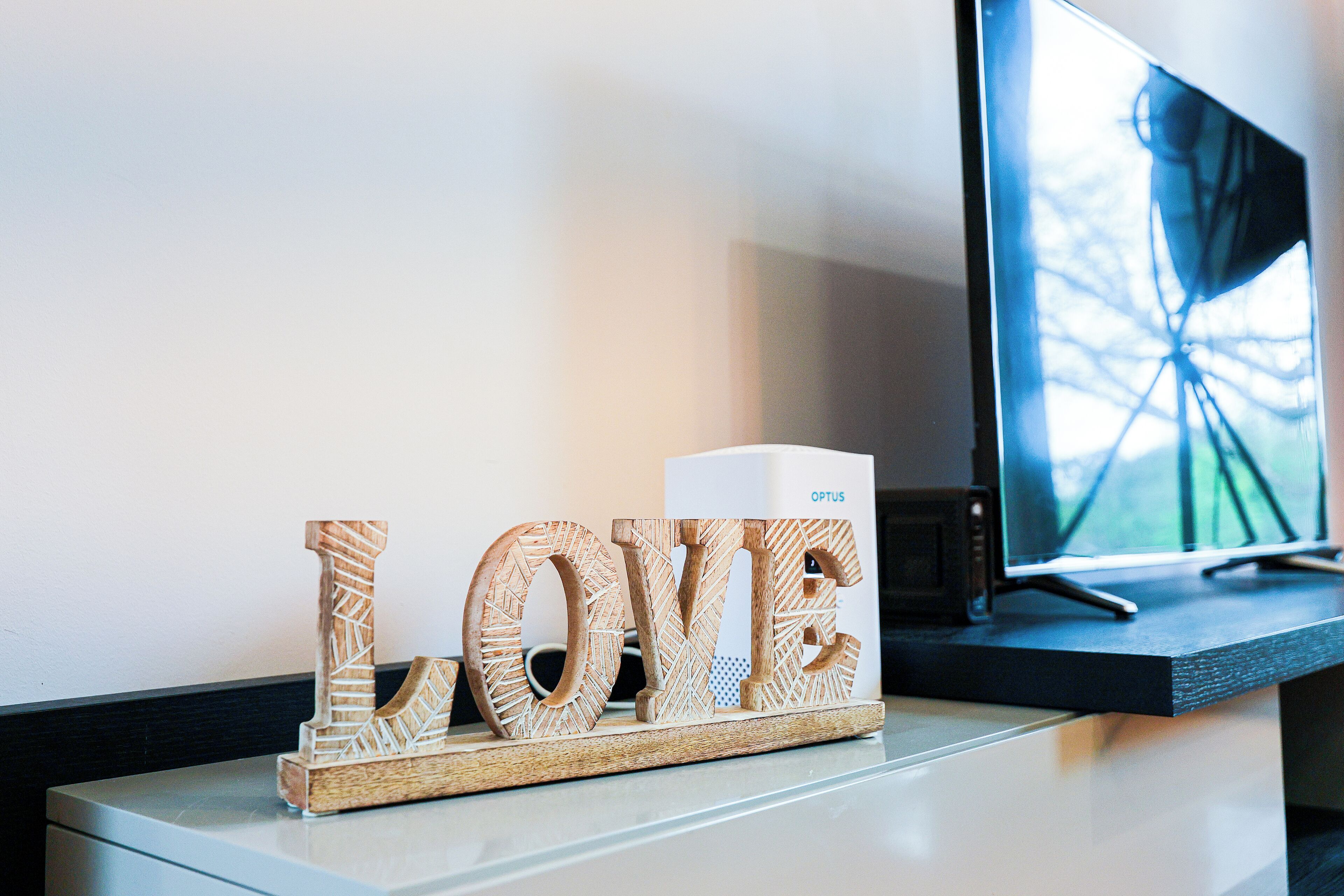 A wooden block with the word "LOVE" on a desk next to a computer monitor.