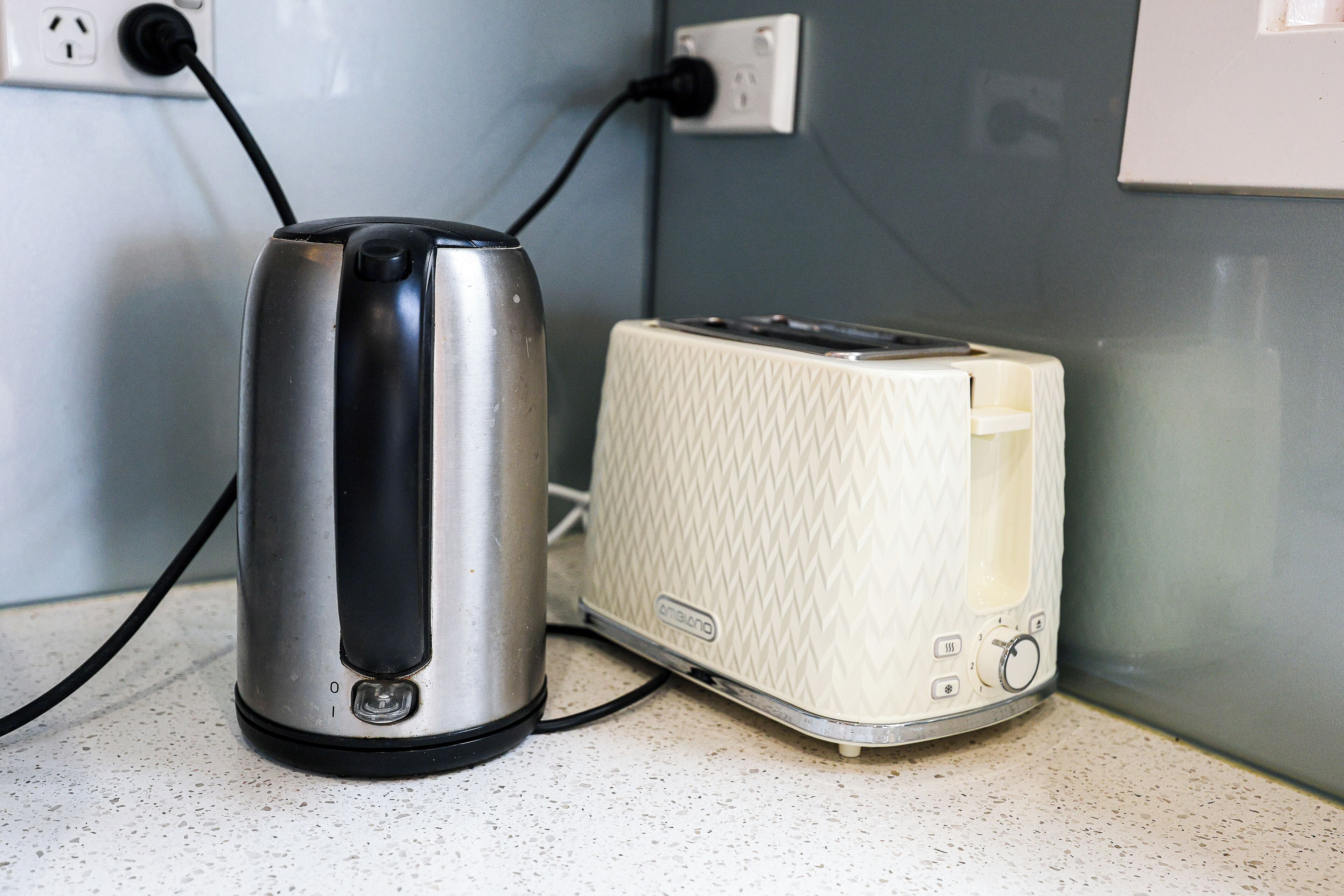 Ein Wasserkocher und ein Toaster stehen auf einer Arbeitsplatte, im Hintergrund ist eine Steckdose zu sehen.