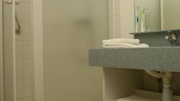 Een badkamer met een douche, een wastafel met spiegel en een handdoekrek.
