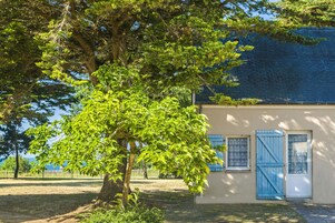A building with a blue door and windows, surrounded by trees and a fence.