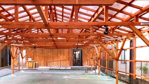 A wooden structure with a metal roof, a black door, and a concrete floor. - Mori no Guest House - Hostel (Tenri)