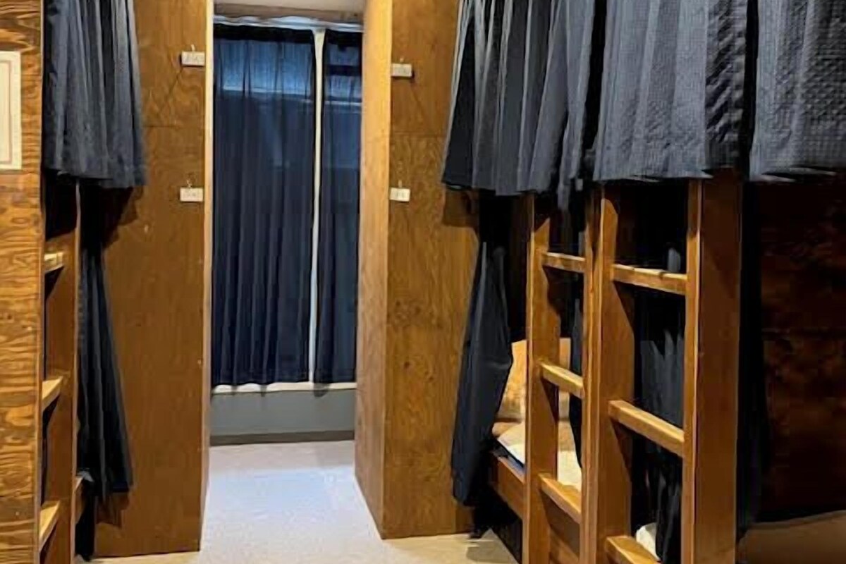 Une pièce avec des lits superposés, des murs en bois et un sol recouvert de moquette.