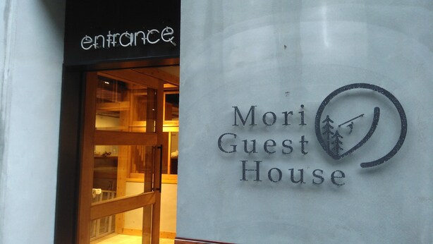The entrance to a hotel named 'Mori Guest House' with a wooden interior visible through the glass door. - Mori no Guest House - Hostel (Tenri)