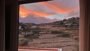 A view from a window overlooking a landscape with buildings and a sunset. - Penthouse Caniço de Baixo (Santa Cruz)