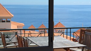 A balcony with a view of the sea and buildings with red roofs. - Penthouse Caniço de Baixo (Santa Cruz)
