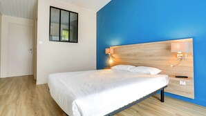Ein modernes Schlafzimmer mit einem Bett, einem Nachttisch, einer Wandlampe und einem Fenster mit Jalousien.