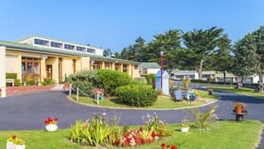 Ein Hotel mit Gründach, einem zentralen Garten mit verschiedenen Pflanzen und Blumen sowie einem Parkplatz.