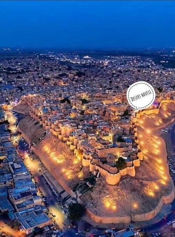 An aerial view of a historic walled city with a prominent fortification, narrow streets, and dense urban layout.