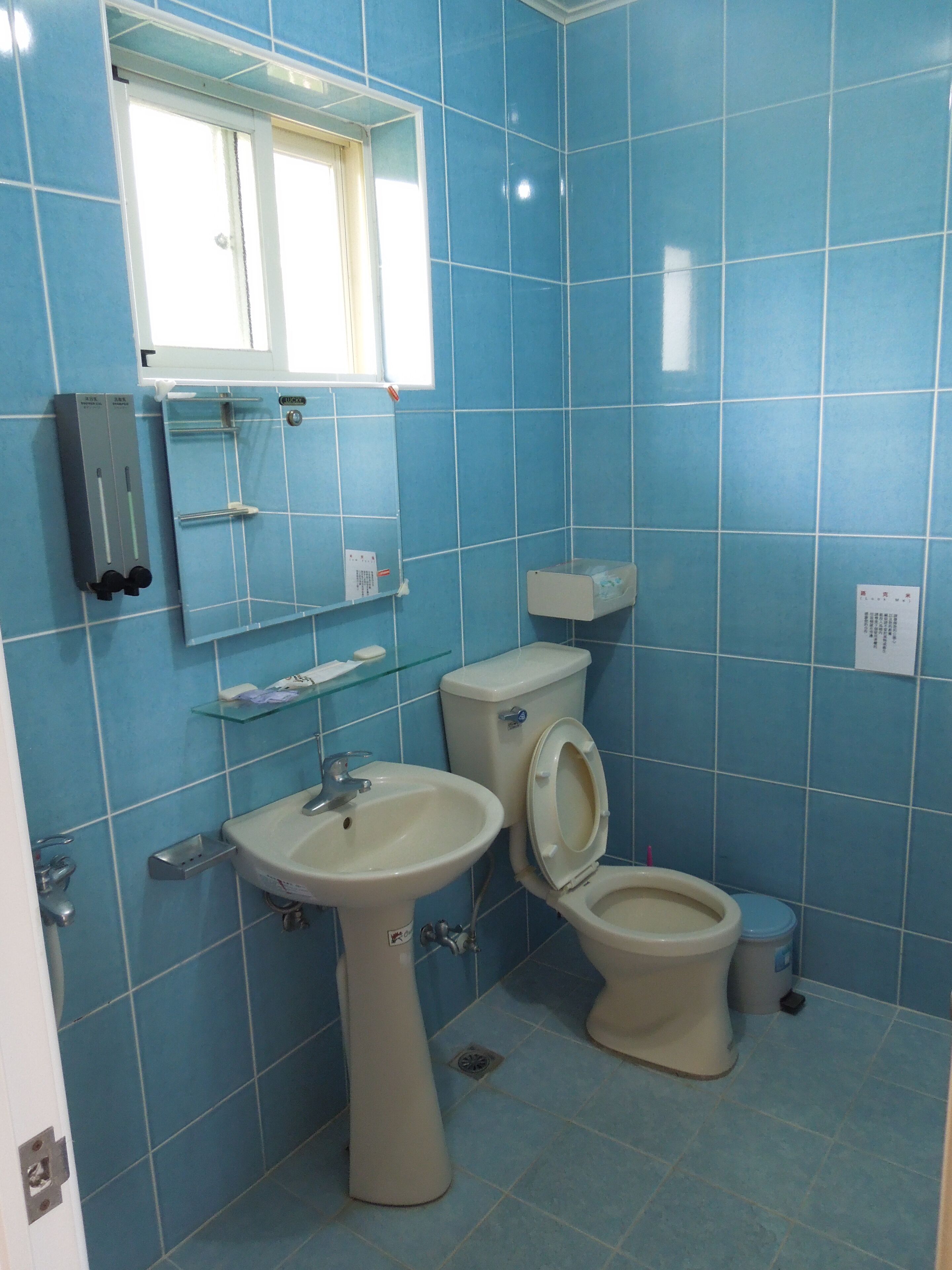 Un baño con azulejos azules, un lavabo, un inodoro y un espejo.