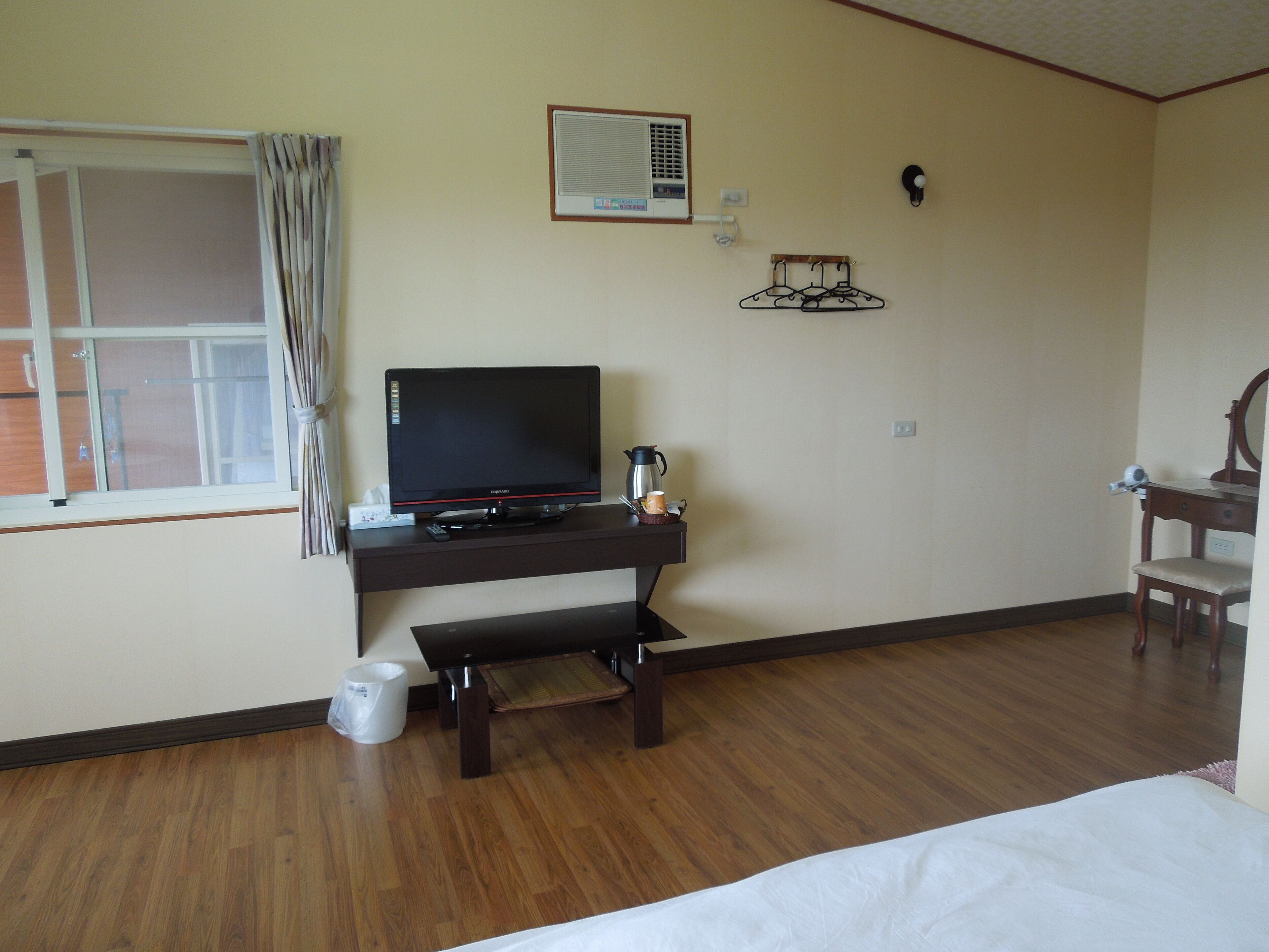 Habitación de hotel con un escritorio de madera, un televisor, una cafetera y una silla.