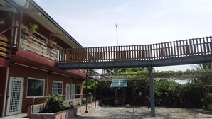 A multi-story building with a balcony, a covered walkway, and a staircase leading to a lower level. - Dulan Red House (Donghe)