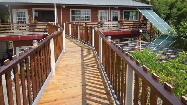 A wooden deck leading to a building with multiple windows and a green awning. - Dulan Red House (Donghe)