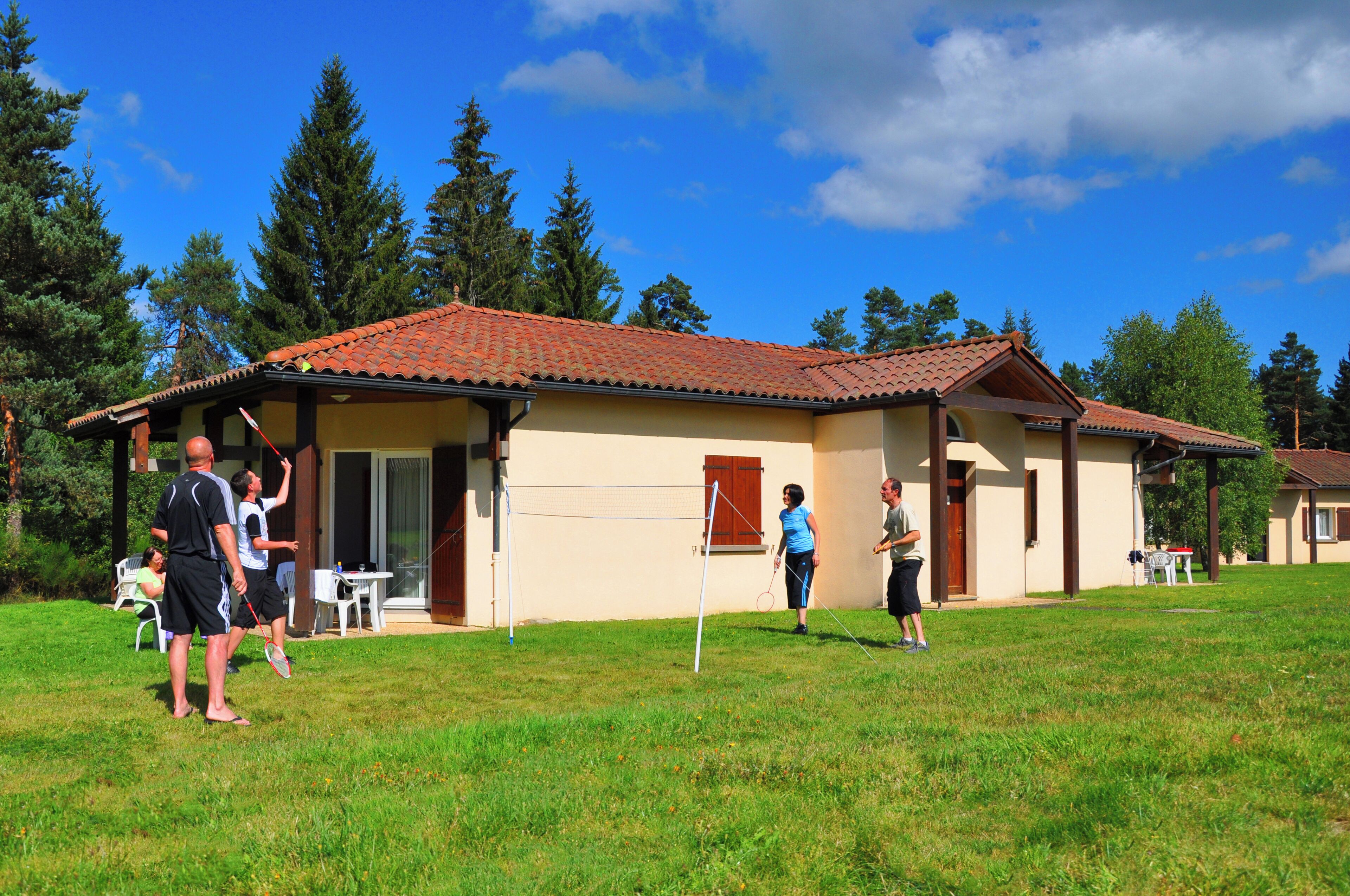 Una casa con techo de tejas, patio y jardín.