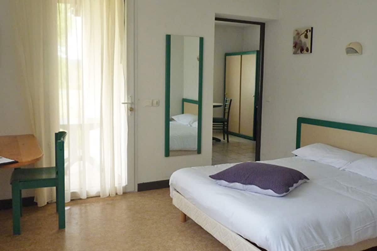 Une chambre d’hôtel avec un lit, une chaise, un bureau et un miroir.