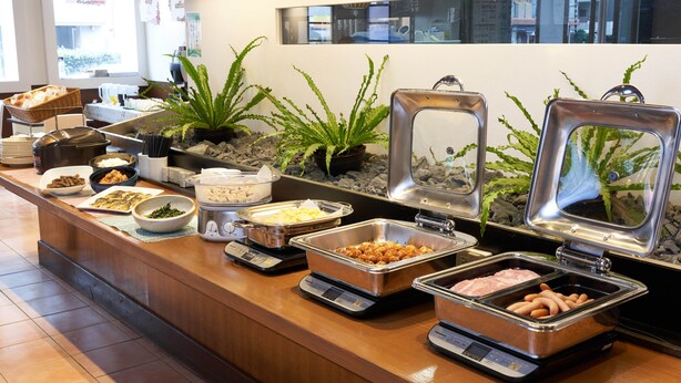 A buffet counter with various food items and a weighing scale. - Hotel First Stay Amagasaki (Amagasaki)
