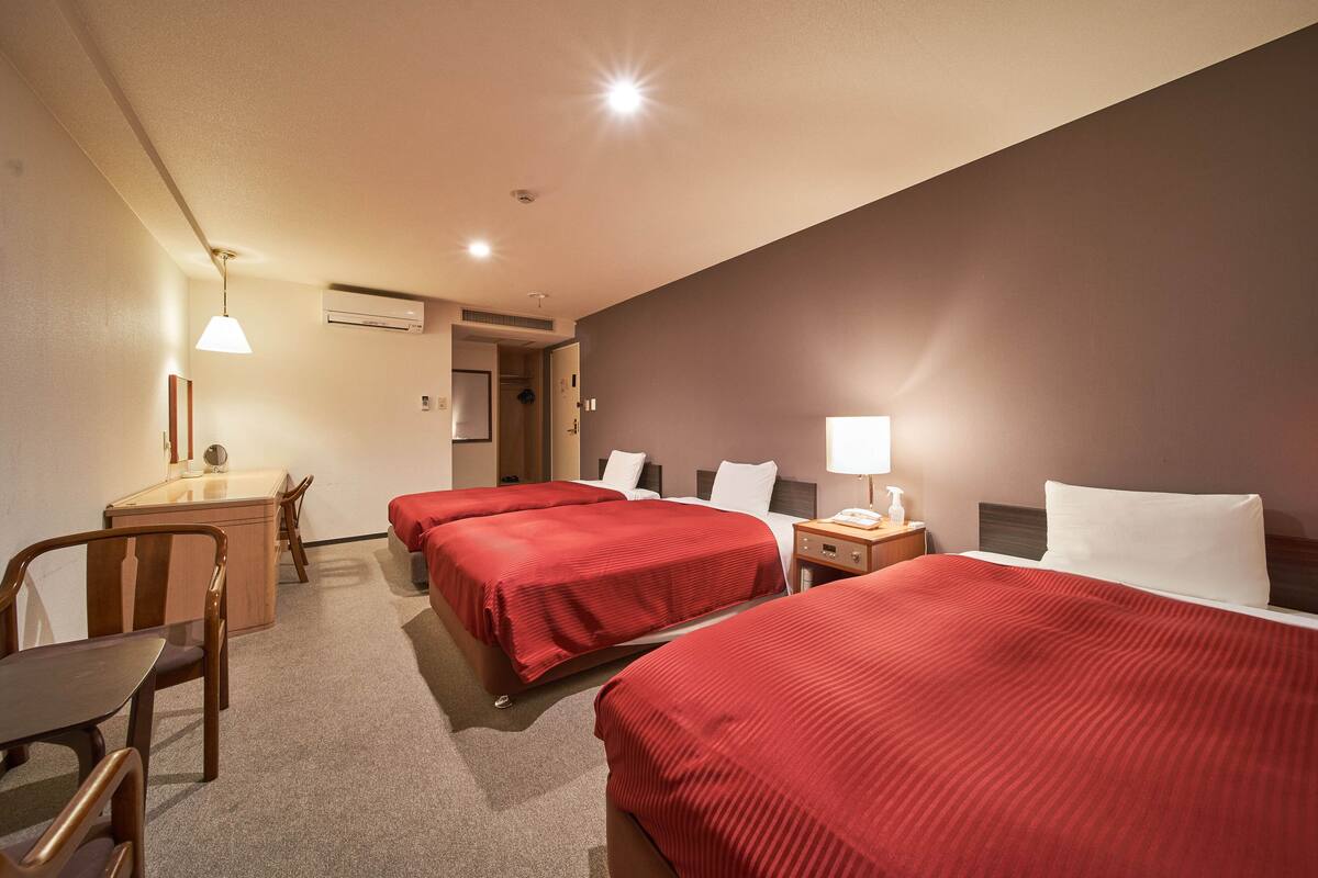 A hotel room with two beds, a desk, and a chair.